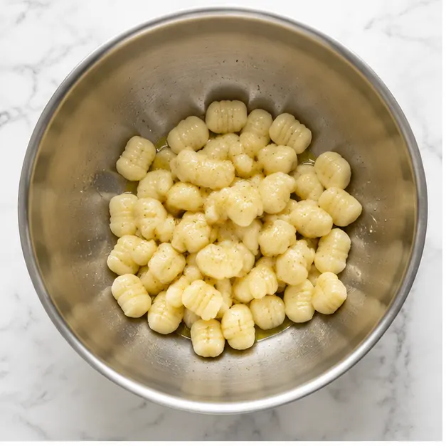 Step 1: Tossing raw gnocchi with olive oil and seasonings