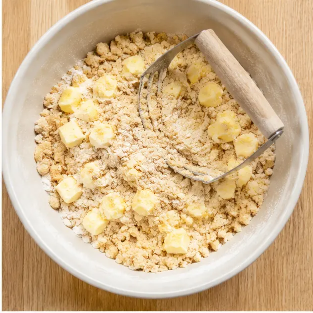 Cut cold butter into the flour mixture until it forms a crumbly, sandy dough that holds together when pinched