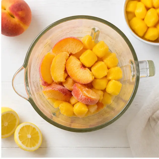 Step 2: Adding frozen peach slices and mango chunks over the liquid