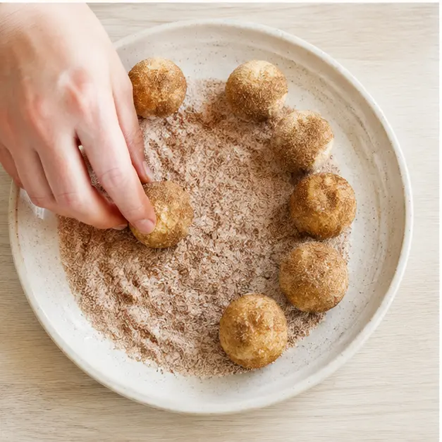 Rolling chilled dough balls in cinnamon sugar