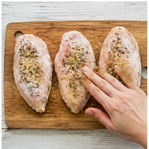 Press garlic herb seasoning onto frozen chicken fillets